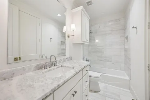 a bathroom with a granite countertop sink a toilet and shower