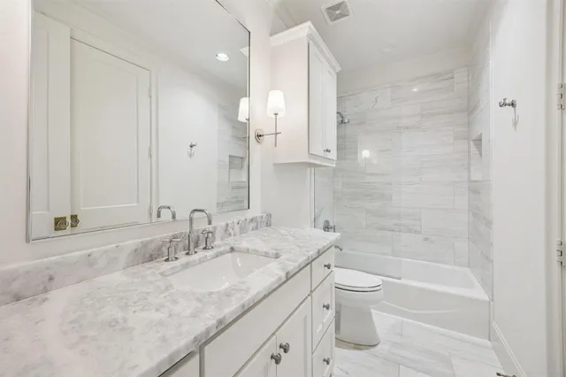 a bathroom with a granite countertop sink a toilet and shower