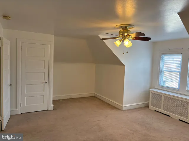 an empty room with chandelier fan and windows