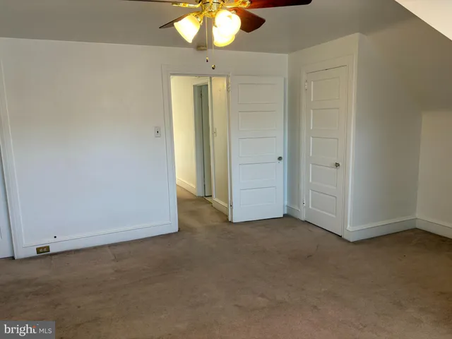 an empty room with a chandelier fan and closet