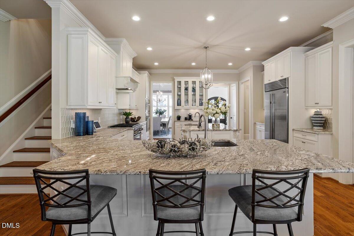1413 Lily Estates Drive Raleigh, NC 27614 - Photo 30 of 82 a kitchen with stainless steel appliances granite countertop sink stove and white cabinets with wooden floor