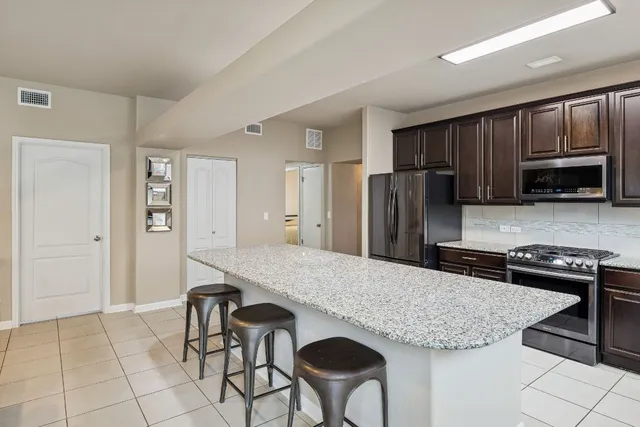 a kitchen with stainless steel appliances granite countertop a refrigerator a stove a sink dishwasher and a refrigerator with wooden floor