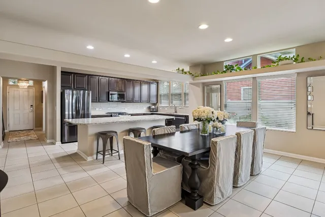 a kitchen with stainless steel appliances granite countertop a table chairs and a refrigerator