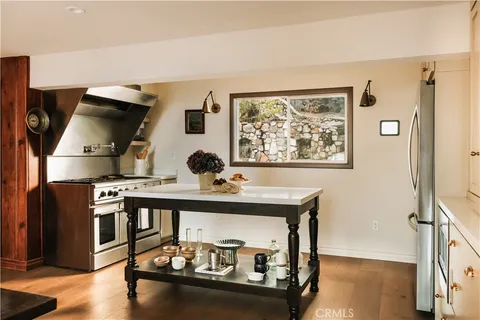 a view of kitchen island with stainless steel appliances wooden floor and chair