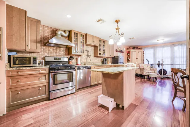 a kitchen with stainless steel appliances a stove a sink dishwasher a refrigerator oven and white cabinets with wooden floor