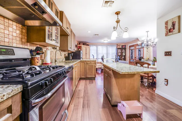a kitchen with stainless steel appliances granite countertop a stove and a wooden floors