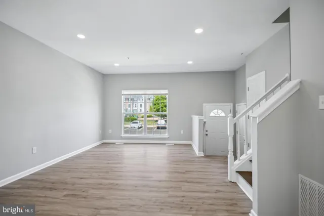 a view of empty room with wooden floor and window