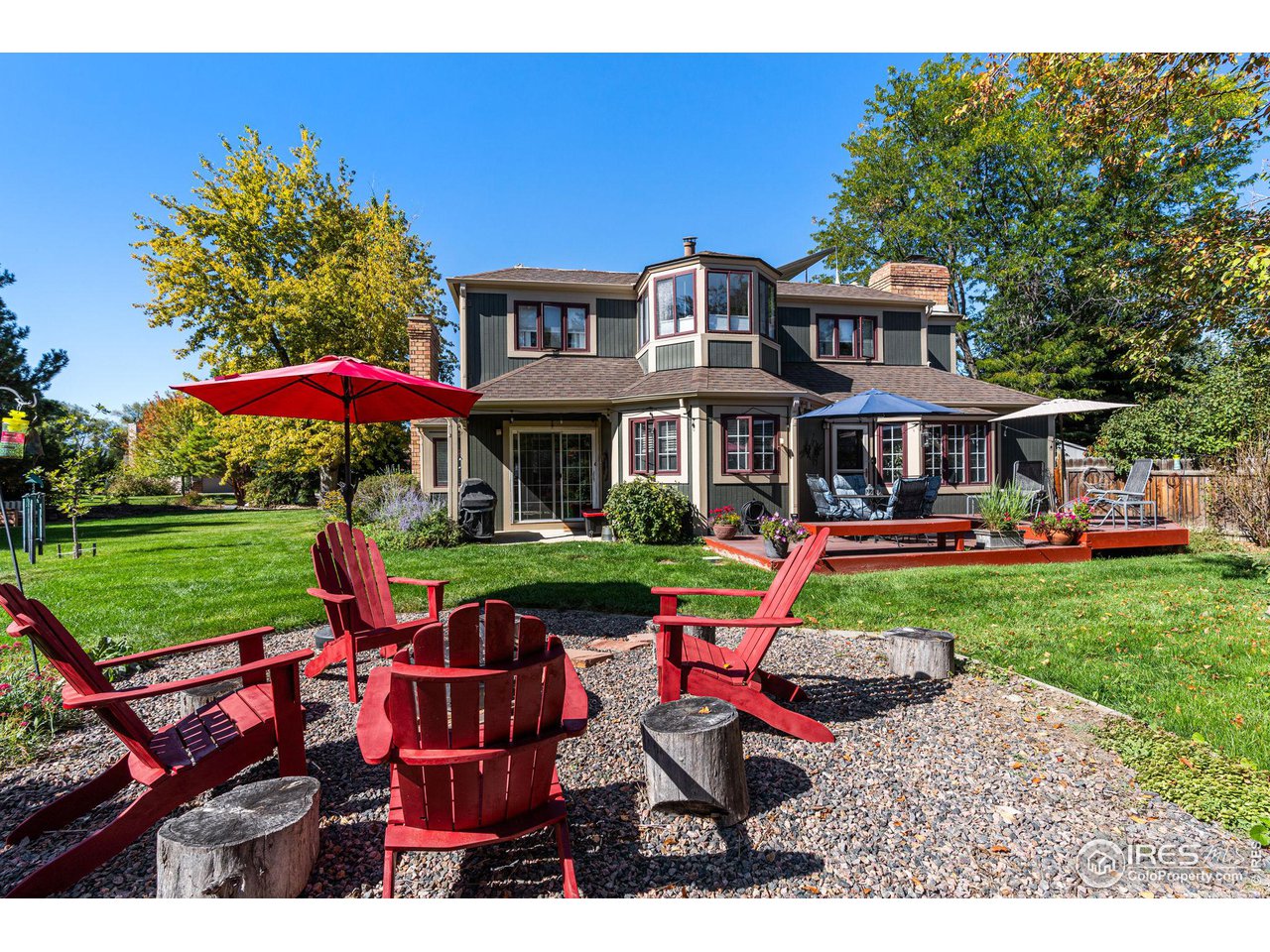 6850 Frying Pan Road Boulder, CO 80301 - Photo 1 of 40 Beautifully landscaped backyard with a deck, raised garden beds, a cozy fire pit area, and mature trees that offer privacy