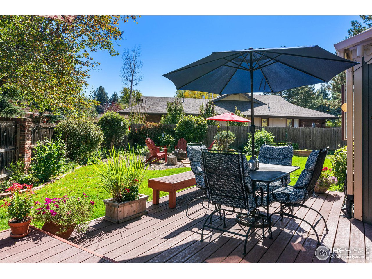 6850 Frying Pan Road Boulder, CO 80301 - Photo 2 of 40 Beautifully landscaped backyard with a deck, raised garden beds, a cozy fire pit area, and mature trees that offer privacy