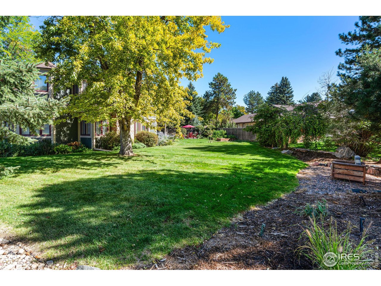 6850 Frying Pan Road Boulder, CO 80301 - Photo 32 of 40 Beautifully landscaped backyard with a deck, raised garden beds, a cozy fire pit area, and mature trees that offer privacy