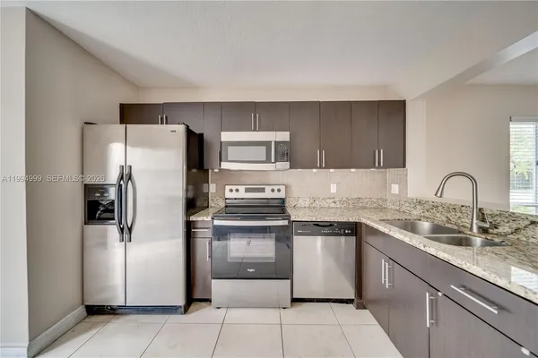 a kitchen with stainless steel appliances granite countertop a refrigerator sink and stove