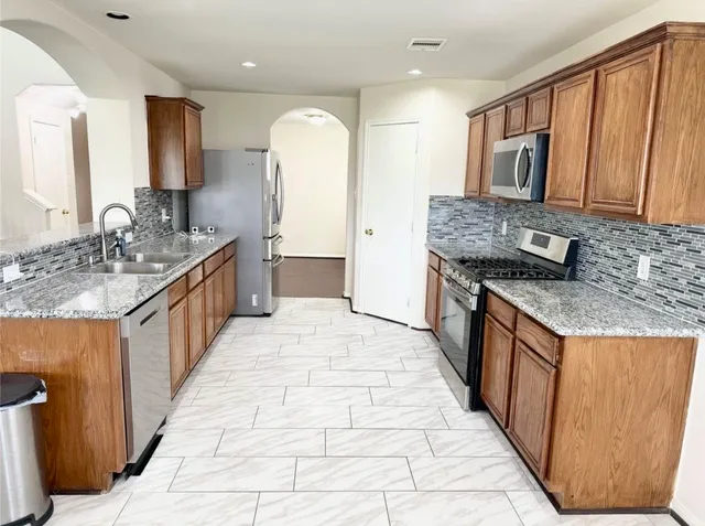 a kitchen with stainless steel appliances granite countertop a sink stove and cabinets