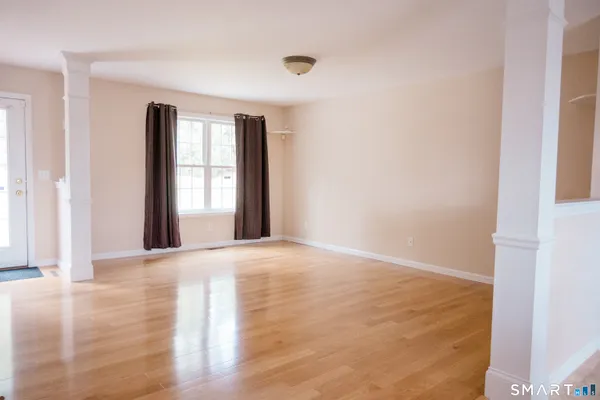 a view of an empty room with wooden floor and a window