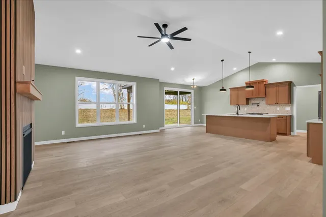 a view of an empty room with a window and a kitchen