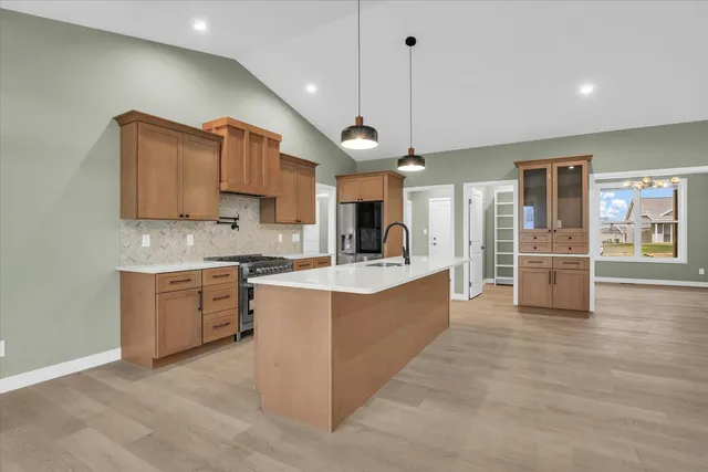 a large kitchen with stainless steel appliances kitchen island granite countertop a stove a sink a refrigerator and a view of living room