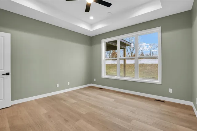 a view of an empty room with a window and wooden floor