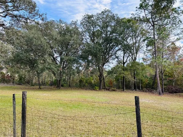 an empty room with wooden floor fireplace and windows