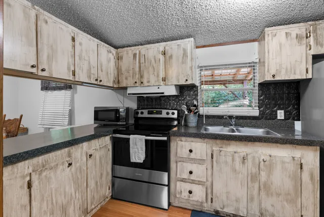 a kitchen with granite countertop a sink a counter top space appliances and cabinets