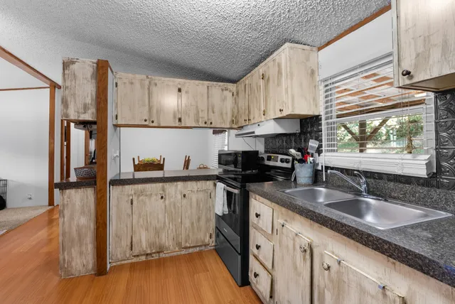 a kitchen with stainless steel appliances granite countertop a refrigerator a stove and a sink with wooden floor