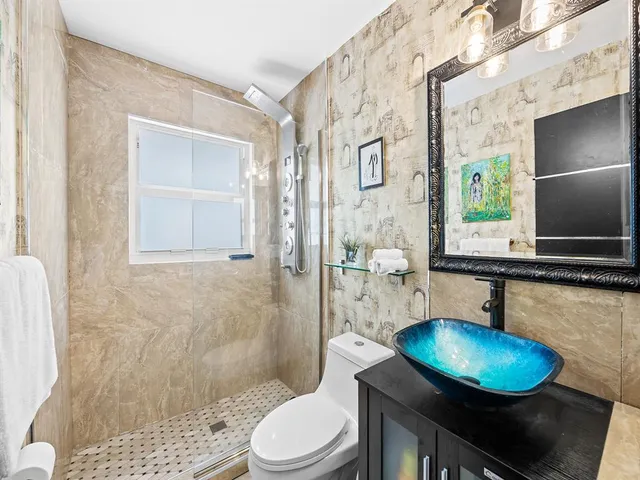 a bathroom with a sink a toilet a mirror and shower