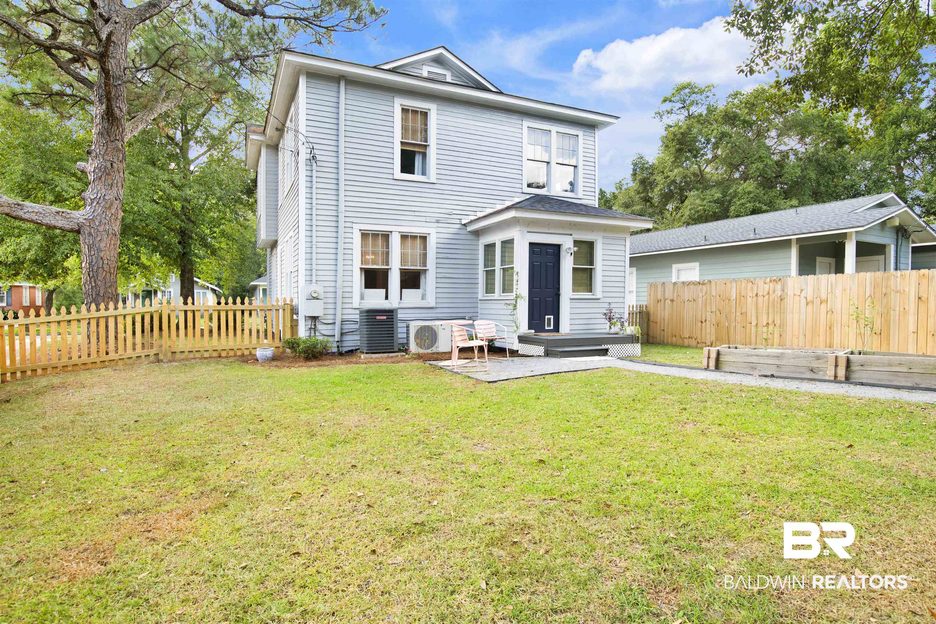 123 Macy Place Mobile, AL 36604 - Photo 3 of 35 Back of property featuring a fenced backyard, a patio area, and a vegetable garden