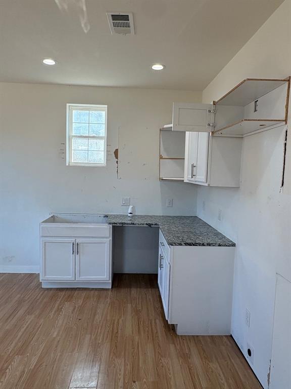 4209 Metropolitan Avenue Dallas, TX 75210 - Photo 5 of 16 a kitchen with a wooden floor and white cabinets