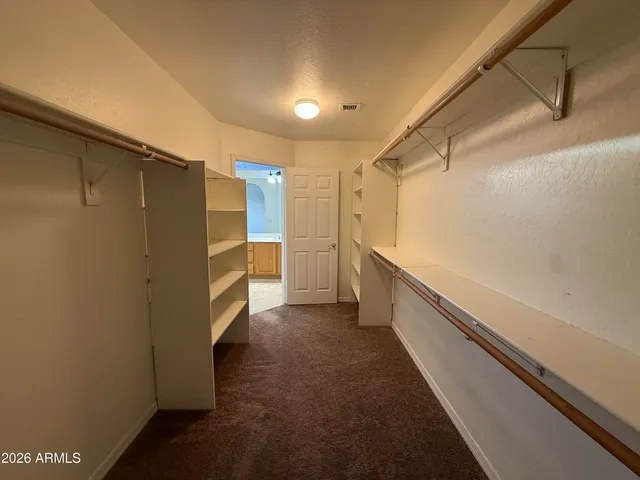 a view of walk in closet with clothes and shoes