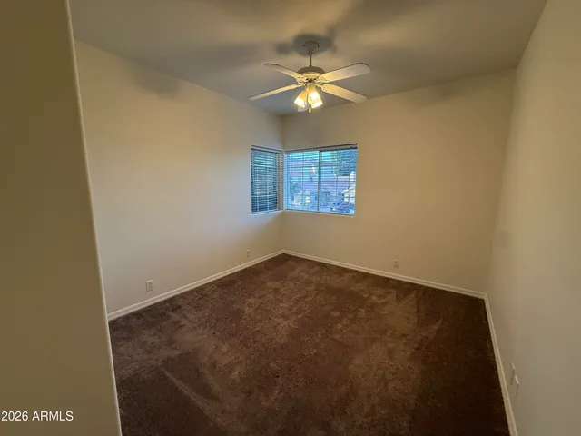 an empty room with a chandelier fan and windows
