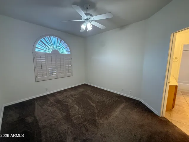 an empty room with windows and ceiling fan