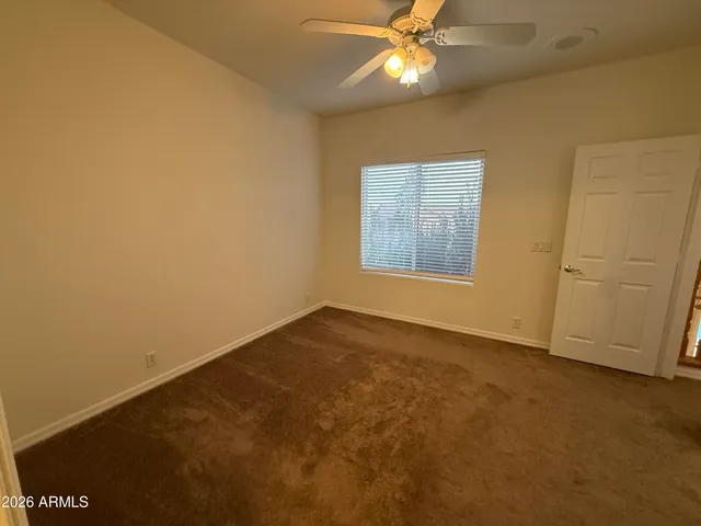 an empty room with a ceiling fan and a window