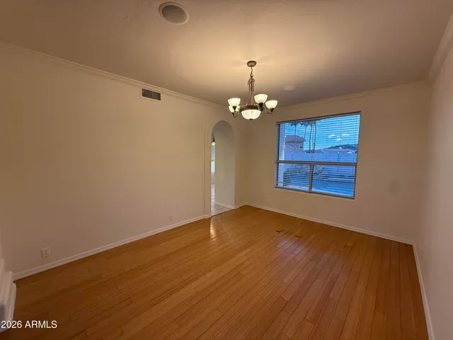 an empty room with wooden floor chandelier fan and windows