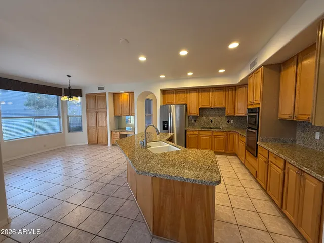 a large kitchen with kitchen island granite countertop a large window and stainless steel appliances