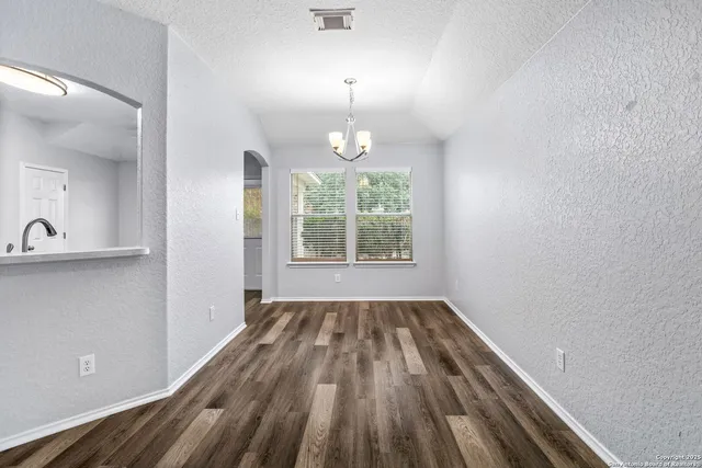 a view of a hallway with wooden floor and a bathroom