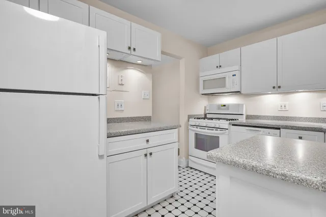 a kitchen with granite countertop white cabinets and white appliances