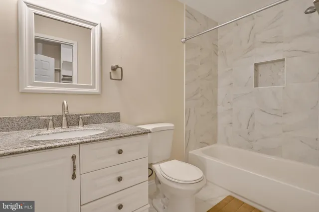 a bathroom with a granite countertop sink toilet and shower