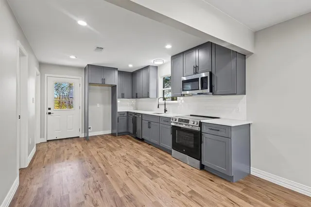 a large kitchen with cabinets wooden floor and stainless steel appliances