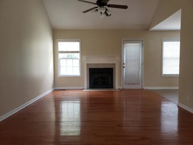 an empty room with wooden floor fireplace and windows