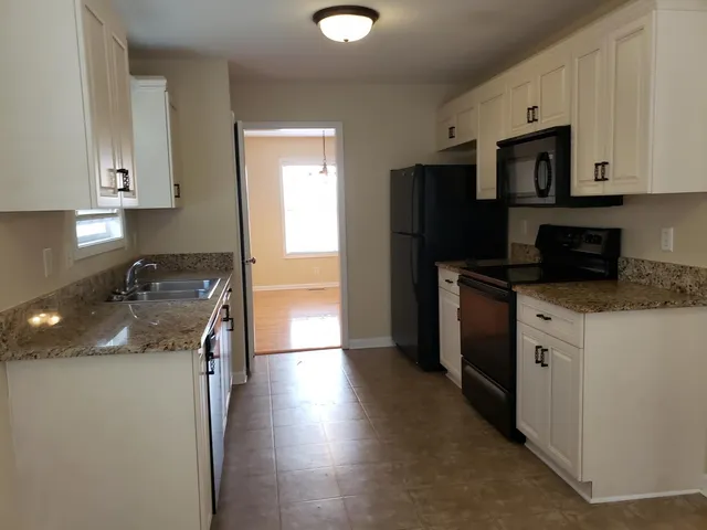 a kitchen with granite countertop a refrigerator stove and sink