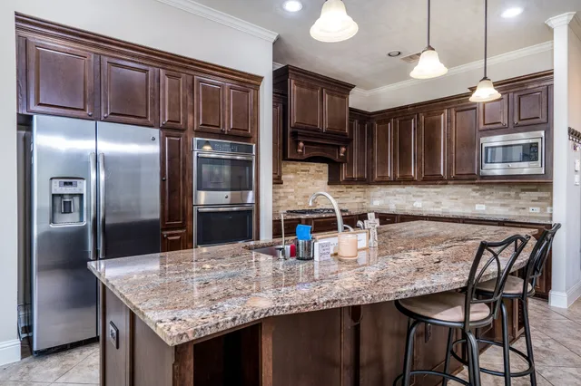 a kitchen with stainless steel appliances granite countertop a sink refrigerator and microwave