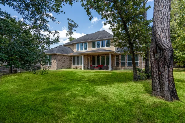 a view of a brick house with a big yard and large trees