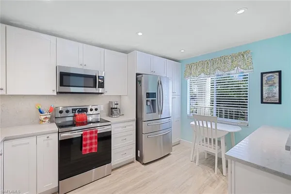a kitchen with granite countertop a refrigerator and a stove top oven