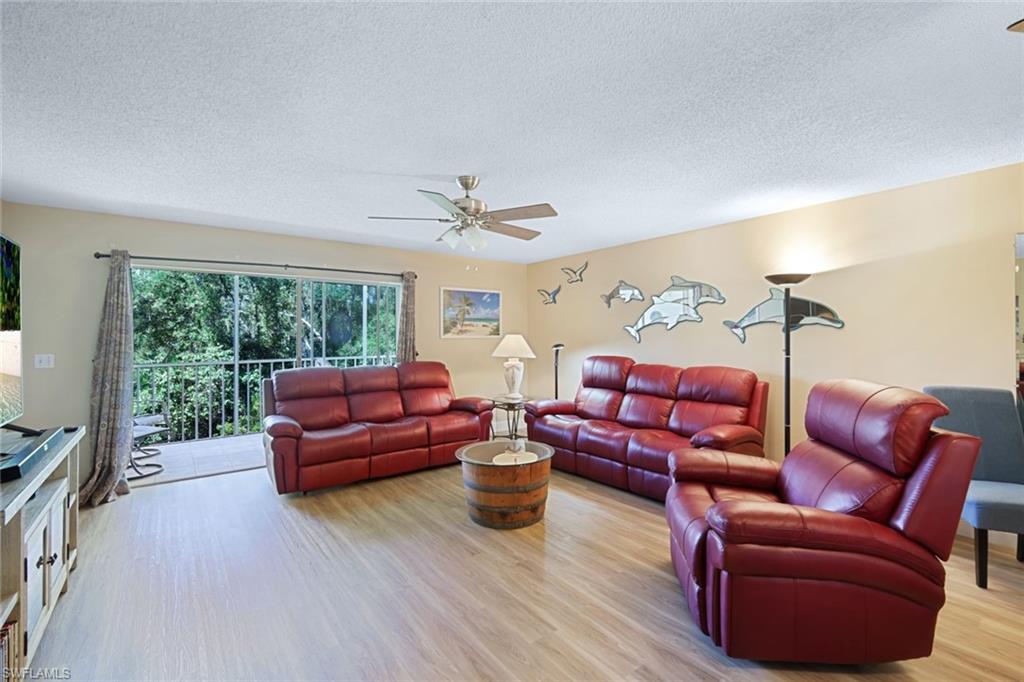 3041 Sandpiper Bay Circle, Unit H203 Naples, FL 34112 - Photo 6 of 23 a living room with furniture large window and wooden floor