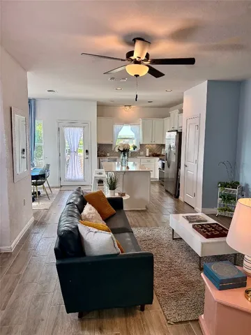 a living room with stainless steel appliances furniture a rug and a chandelier