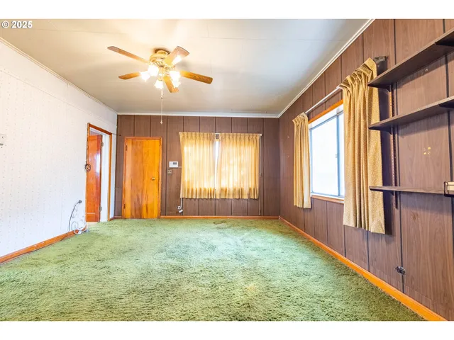 a view of an empty room with window and hardwood floor