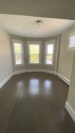 an empty room with wooden floor and windows in it