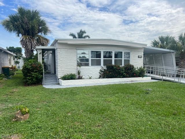 519 Riviera Boulevard East Naples, FL 34112 - Photo 3 of 23 View of front of home featuring an attached carport, stone siding, and a front lawn