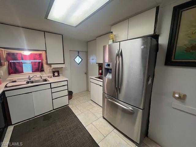 519 Riviera Boulevard East Naples, FL 34112 - Photo 9 of 23 Kitchen with stainless steel fridge with ice dispenser, light countertops, light tile patterned flooring, and white cabinetry