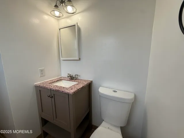 a bathroom with a granite countertop toilet a sink and mirror