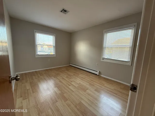 a view of an empty room with a window and wooden floor
