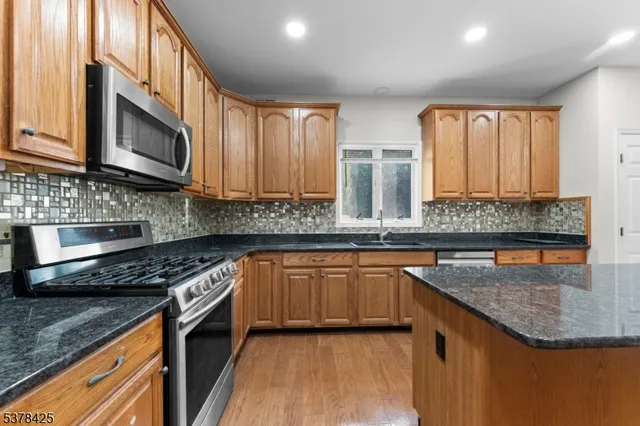 a kitchen with stainless steel appliances granite countertop a stove a sink and a microwave